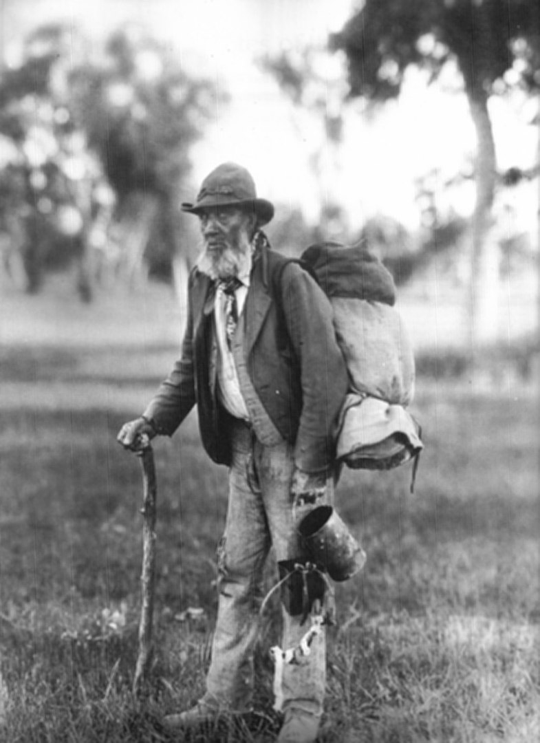 An old black and white photo of a swagman.