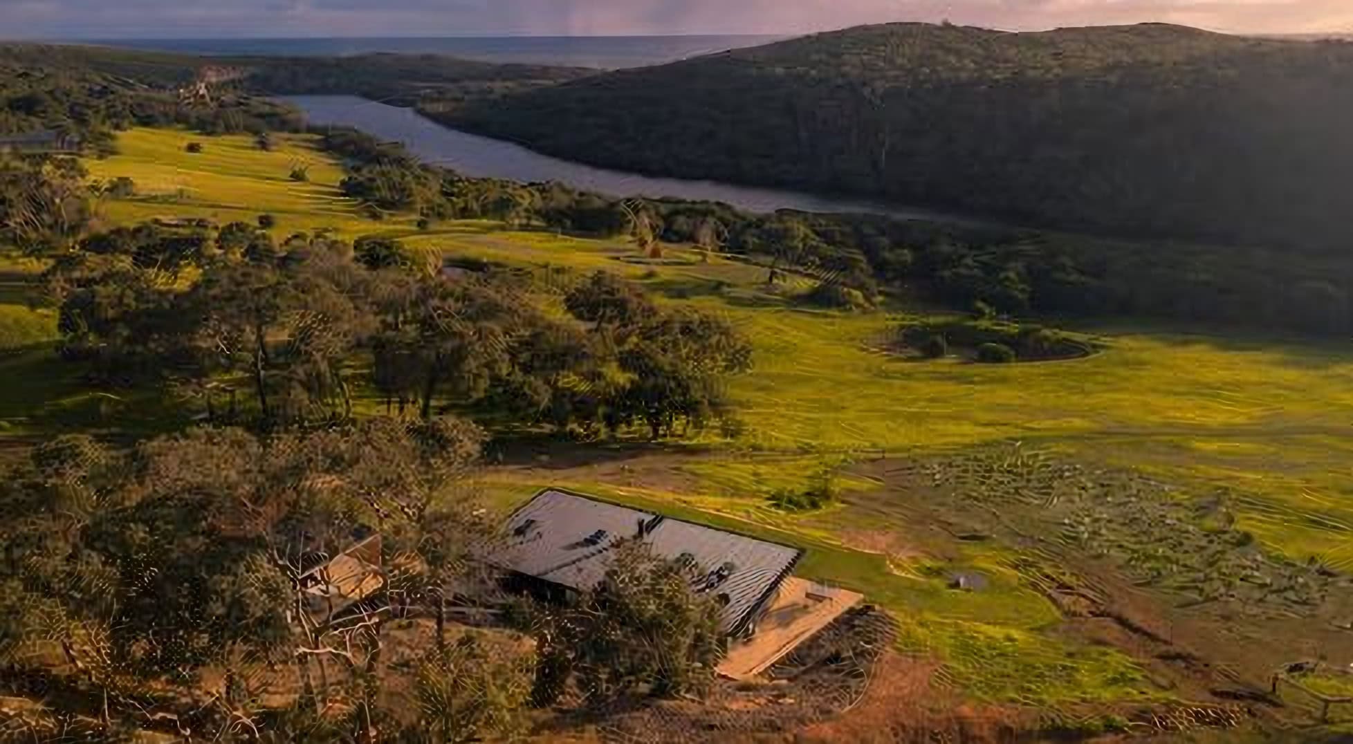 Aerial view of lush green fields and a river in rural Australia, showcasing iconic landscapes of The Jolly Swagman.